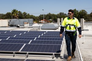 EnergyTec Technician walks next to Solar PV panels
